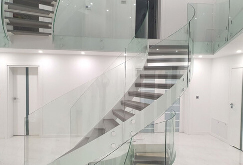Nowoczesne schody zawijane ze szklaną balustradą